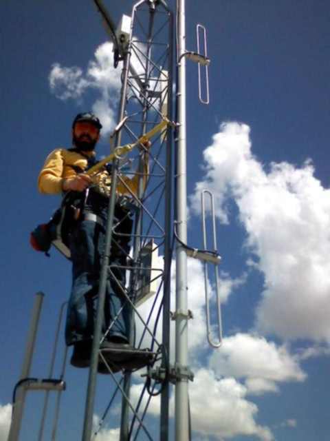 Picture of Brett climbing a radio tower to install a wireless Internet access point